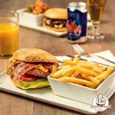 a sandwich and french fries on a white plate with orange juice in the glass next to it