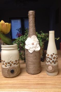 three vases are sitting on a table with flowers in them and one is empty