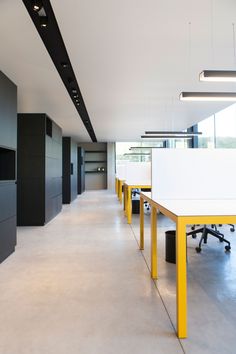 an empty office with yellow and white tables in the center, and black cabinets on either side