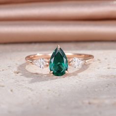 an emerald and diamond ring sitting on top of a table