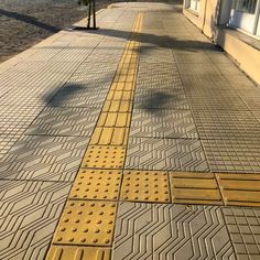 the sidewalk is lined with yellow and black tiles on it's sides, as well as some buildings