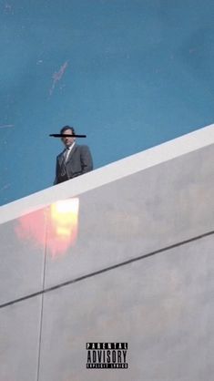 a man in a suit and hat standing on top of a wall