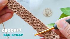 the crochet bag strap is being worked on by someone holding a pen in their left hand