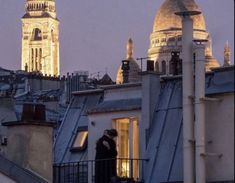 two people are standing on the roof of an apartment building in paris, france at dusk