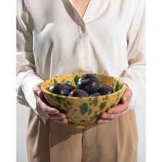 a woman holding a bowl filled with black olives