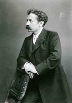 an old black and white photo of a man in a long coat holding a book