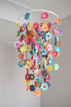 a chandelier with paper flowers hanging from it's sides in a room