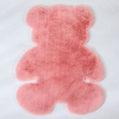 a pink teddy bear rug sitting on top of a white sheet