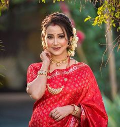 a woman in a red sari and gold jewelry poses for the camera with her hand on her shoulder