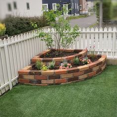 a white picket fence surrounding a garden area with flowers and plants in the center, surrounded by grass