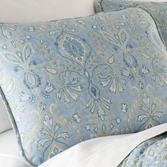 a bed with blue and white pillows on it's side, next to a pillow