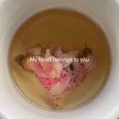 a white bowl filled with water and some pink flowers in the liquid that says, my heart belongs to you