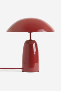 a red table lamp sitting on top of a white floor