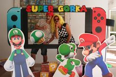 two people are standing in front of a video game display with mario and luigi paper cutouts