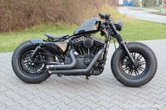 a black motorcycle parked on top of a sidewalk