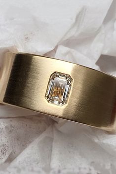 a close up of a gold ring with a diamond in the center on white paper