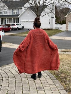 a woman is walking down the sidewalk in a red coat