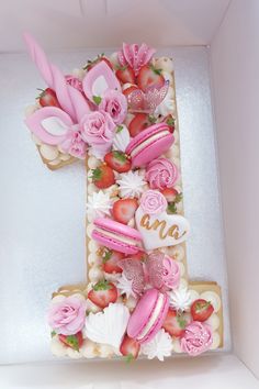 the letter f is decorated with pink icing and flowers, including strawberries and roses