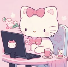 a hello kitty sitting at a table with a laptop and coffee cup in front of it