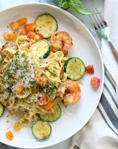 pasta with shrimp, zucchini and parmesan cheese on a white plate