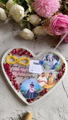 a heart shaped box filled with photos and flowers next to a corkscrew marker