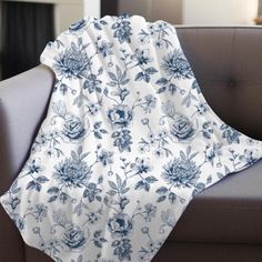 a blue and white flowered blanket sitting on top of a couch next to a chair