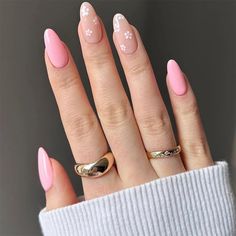 a woman's hand with pink and white nail polish on her nails, wearing a gold ring