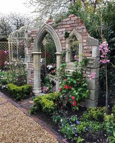 the garden is full of flowers and plants, including an arch in the middle of it