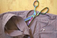 a pair of scissors sitting on top of a checkered shirt next to some scissors