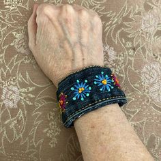 an older woman's arm wearing a blue bracelet with flowers on it and beading