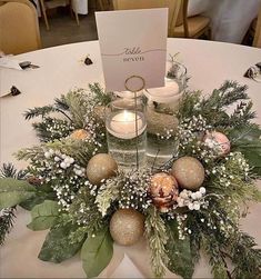 a centerpiece with candles, greenery and ornaments on a table at a wedding reception