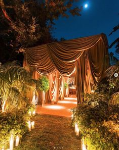 an outdoor wedding venue with lights and drapes on the canopy, surrounded by lush greenery