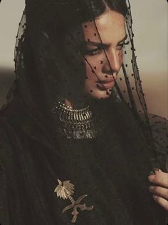 a woman with black veil and gold jewelry