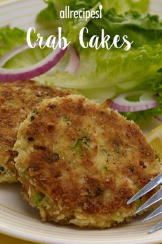 crab cakes with lettuce and lemon wedges are on a plate next to a fork