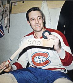 a man sitting in a chair holding a wooden sign with the number 600 on it