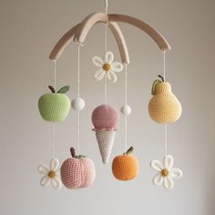 crocheted apples and an ice cream cone hanging from a wooden mobile with flowers