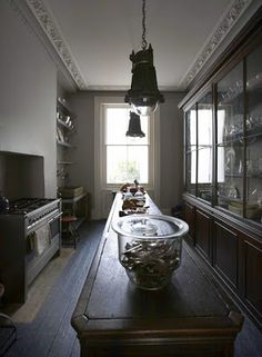 an old fashioned kitchen with lots of glassware on the counter and wooden flooring