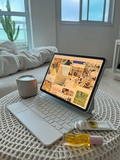 an open laptop computer sitting on top of a bed next to a cup and saucer