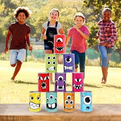 three girls and two boys are playing with blocks made to look like monster faces in the yard