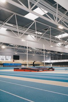 a man riding a skateboard on top of a blue and red track in a gym