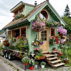 a green house with flowers on the windows and steps leading up to it's front door