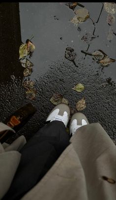 the person is standing in front of water with leaves on it and wearing white shoes