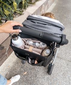 a person is pulling a stroller with items in it and holding onto the handle