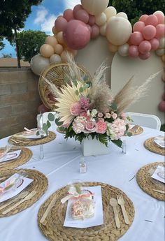 a table topped with lots of plates covered in flowers and cake next to balloon decorations