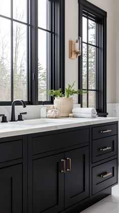 a black and white bathroom with double sinks, large windows, and gold handles on the faucet