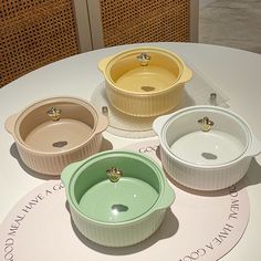 four different colored dishes sitting on top of a white table