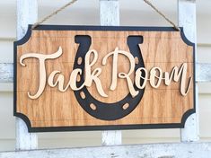 a wooden sign hanging from the side of a building that says tack room on it