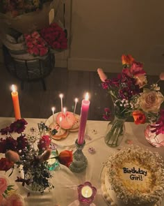 a table topped with cakes and candles next to vases filled with flowers on top of a table