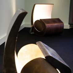 two large metal sculptures sitting on top of a black carpeted floor next to a white wall