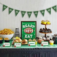 a football themed party with snacks and desserts on a green tableclothed table